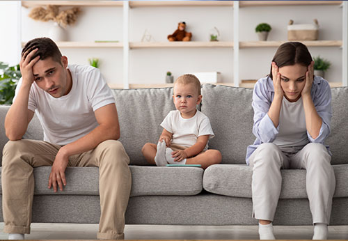 Stressed parents with a child sitting on a couch, symbolizing family law challenges.